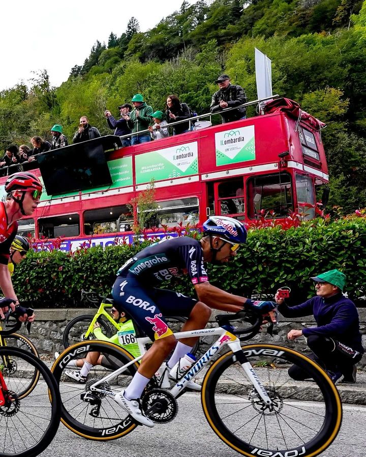 Ciclisti gareggiano con tifosi su bus rosso